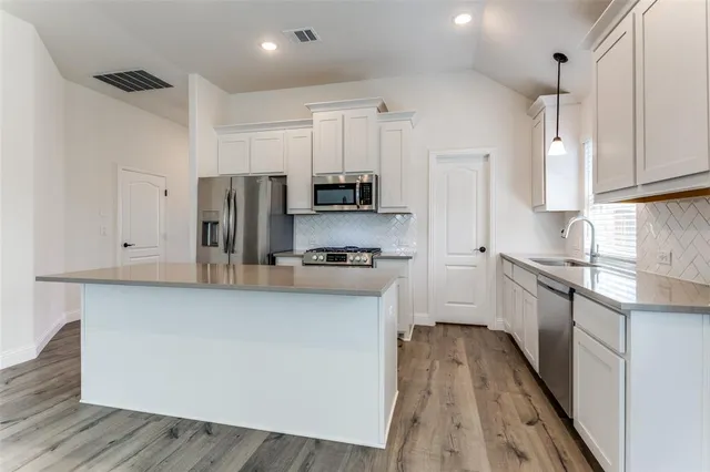 a kitchen with stainless steel appliances a refrigerator sink and white cabinets