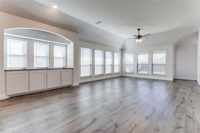 a view of an empty room with a window and wooden floor