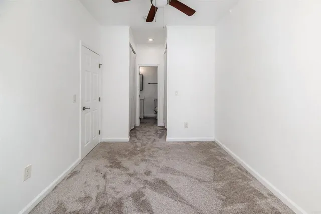 an empty room with chandelier fan and closet