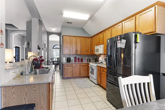 a kitchen with stainless steel appliances granite countertop a refrigerator a sink dishwasher a stove with wooden cabinets