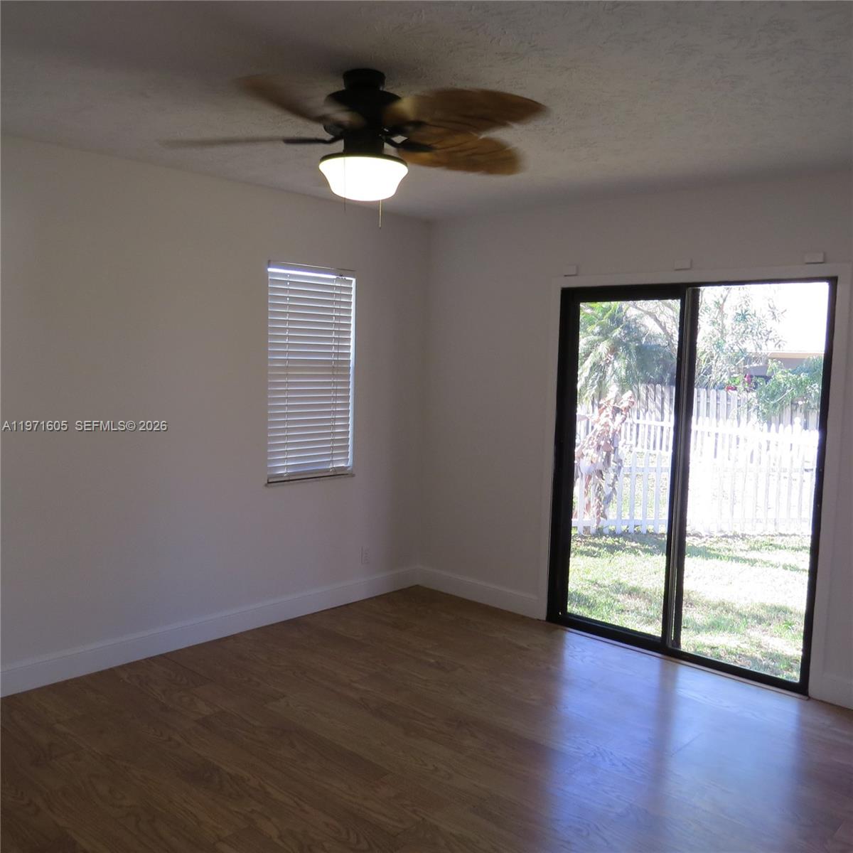 6883 Southeast Raintree Avenue Stuart, FL 34997 - Photo 12 of 32 a view of an empty room with wooden floor and a window