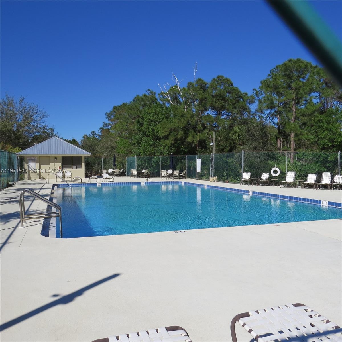 6883 Southeast Raintree Avenue Stuart, FL 34997 - Photo 25 of 32 a view of swimming pool with seating area and trees in the background