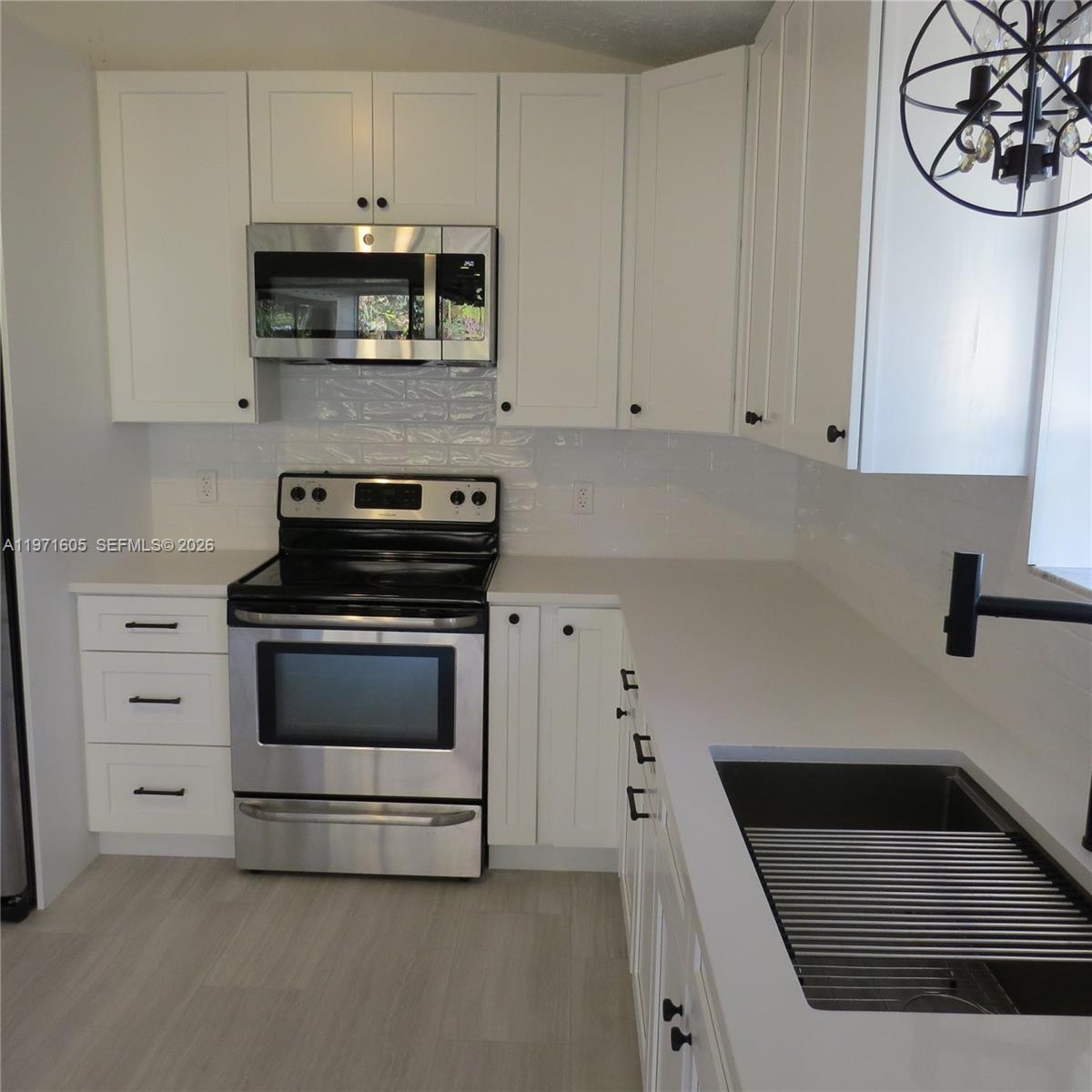 6883 Southeast Raintree Avenue Stuart, FL 34997 - Photo 8 of 32 a kitchen with white cabinets and black appliances