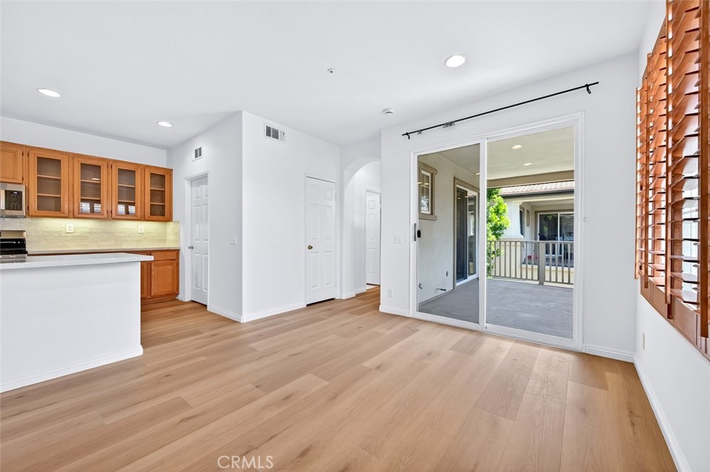 447 Ridgeway Irvine, CA 92620 - Photo 15 of 88 a view of an empty room with wooden floor and a kitchen
