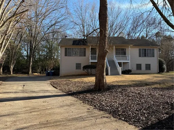 a view of a house with a yard and large tree