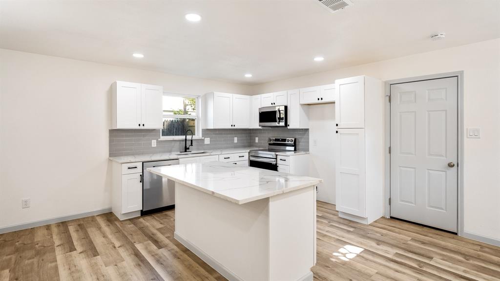 a kitchen with white cabinets and appliances