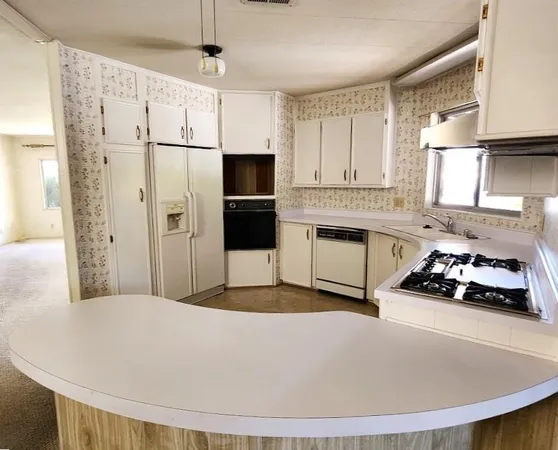a large kitchen with stainless steel appliances kitchen island granite countertop a refrigerator and a stove top oven