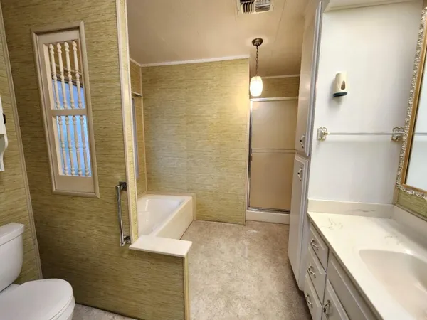 a bathroom with a granite countertop bathtub sink vanity and toilet