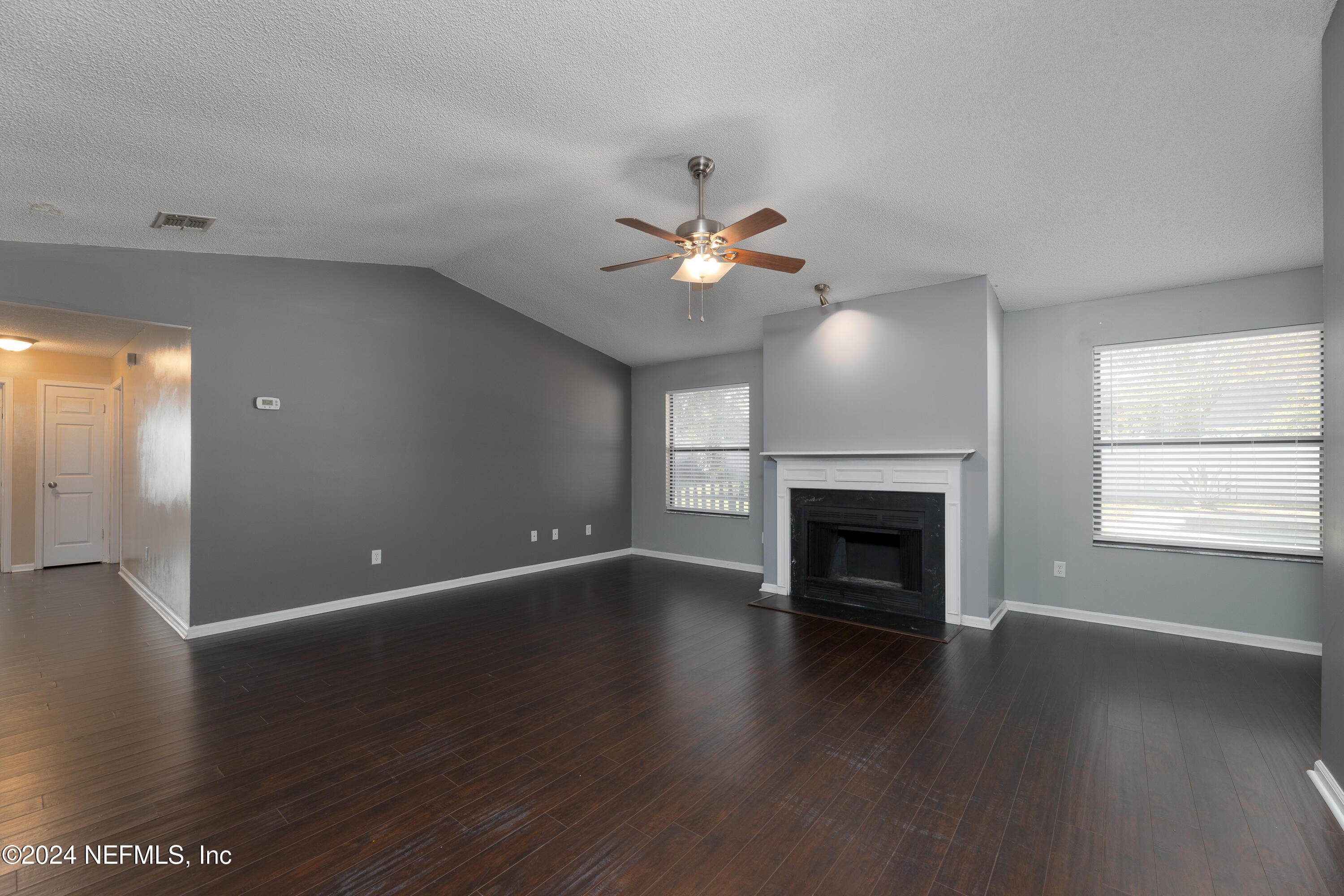 1646 Rusty Rail Road Jacksonville, FL 32225 - Photo 5 of 31 an empty room with windows fireplace and a wooden floor