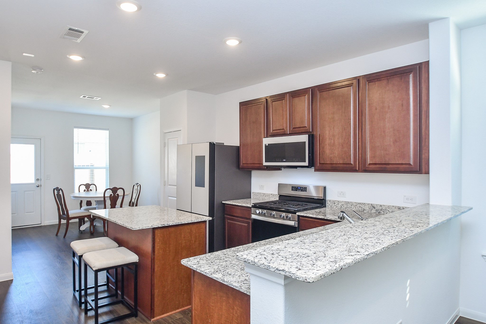 17826 Juneberry Seed Street Hockley, TX 77447 - Photo 11 of 35 a kitchen with stainless steel appliances granite countertop a stove a refrigerator a sink a dining table and chairs