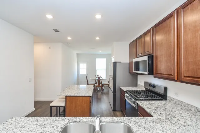 a kitchen with stainless steel appliances granite countertop a stove a refrigerator a sink a dining table and chairs