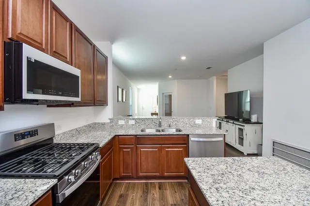 a kitchen with stainless steel appliances granite countertop a sink refrigerator and microwave
