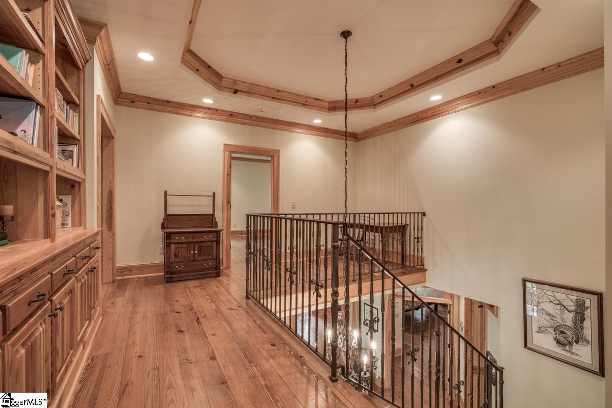 185 Hemlock Cove Road Sunset, SC 29685 - Photo 18 of 36 Hallway at the top of the staircase overlooks the foyer below. Loft area in the far right area could accommodate an easy chair for casual reading and a sitting room is out of sight at the far left of the picture. Wooden accents in the coffered ceiling.