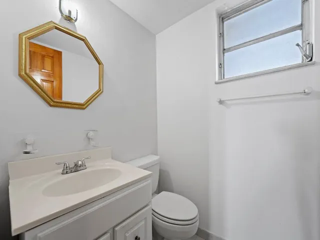 a bathroom with a toilet sink vanity and mirror