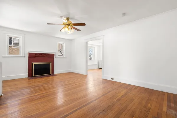 a view of empty room with wooden floor fan and window