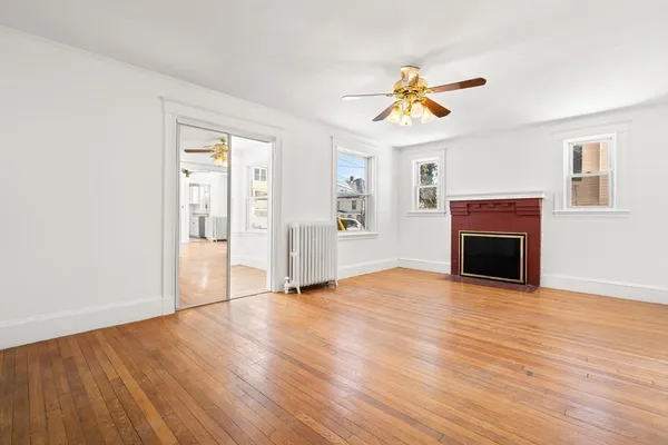 an empty room with wooden floor fireplace and windows