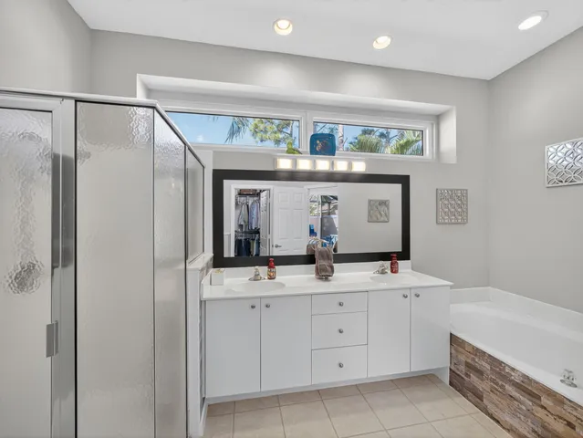 a bathroom with a double vanity sink a mirror a bathtub and shower