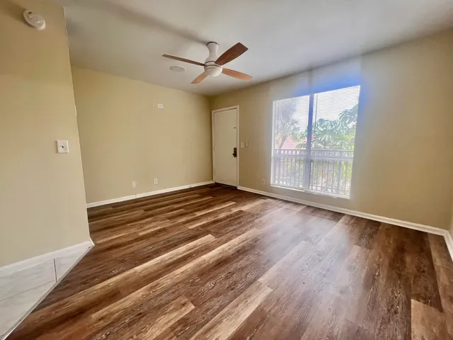 a view of an empty room with wooden floor and a window