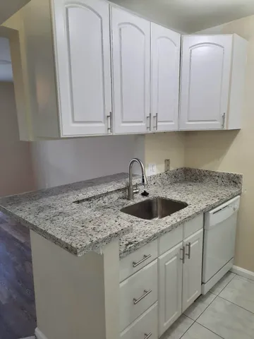 a kitchen with white cabinets and sink