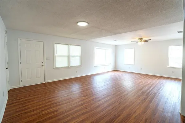 an empty room with wooden floor and windows