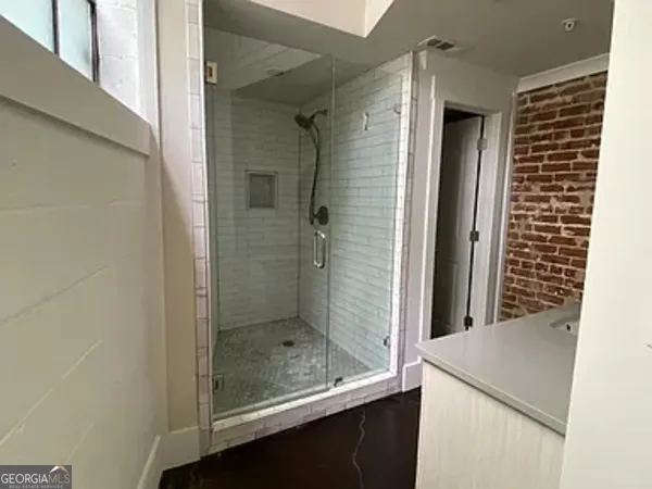 a bathroom with a granite countertop sink a mirror and shower