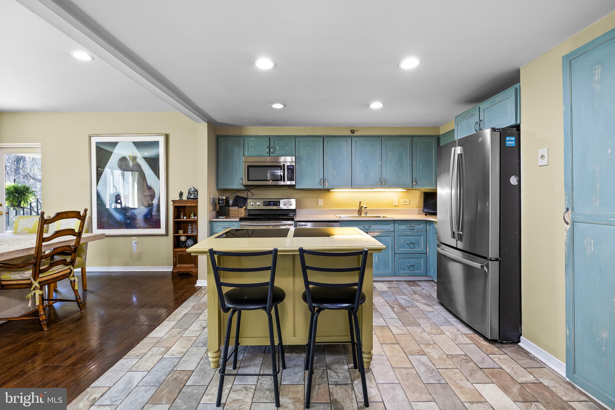 2331 Old Court Road, Unit 307 Baltimore, MD 21208 - Photo 18 of 54 a kitchen with stainless steel appliances granite countertop a refrigerator a stove a sink a dining table and chairs with wooden floor