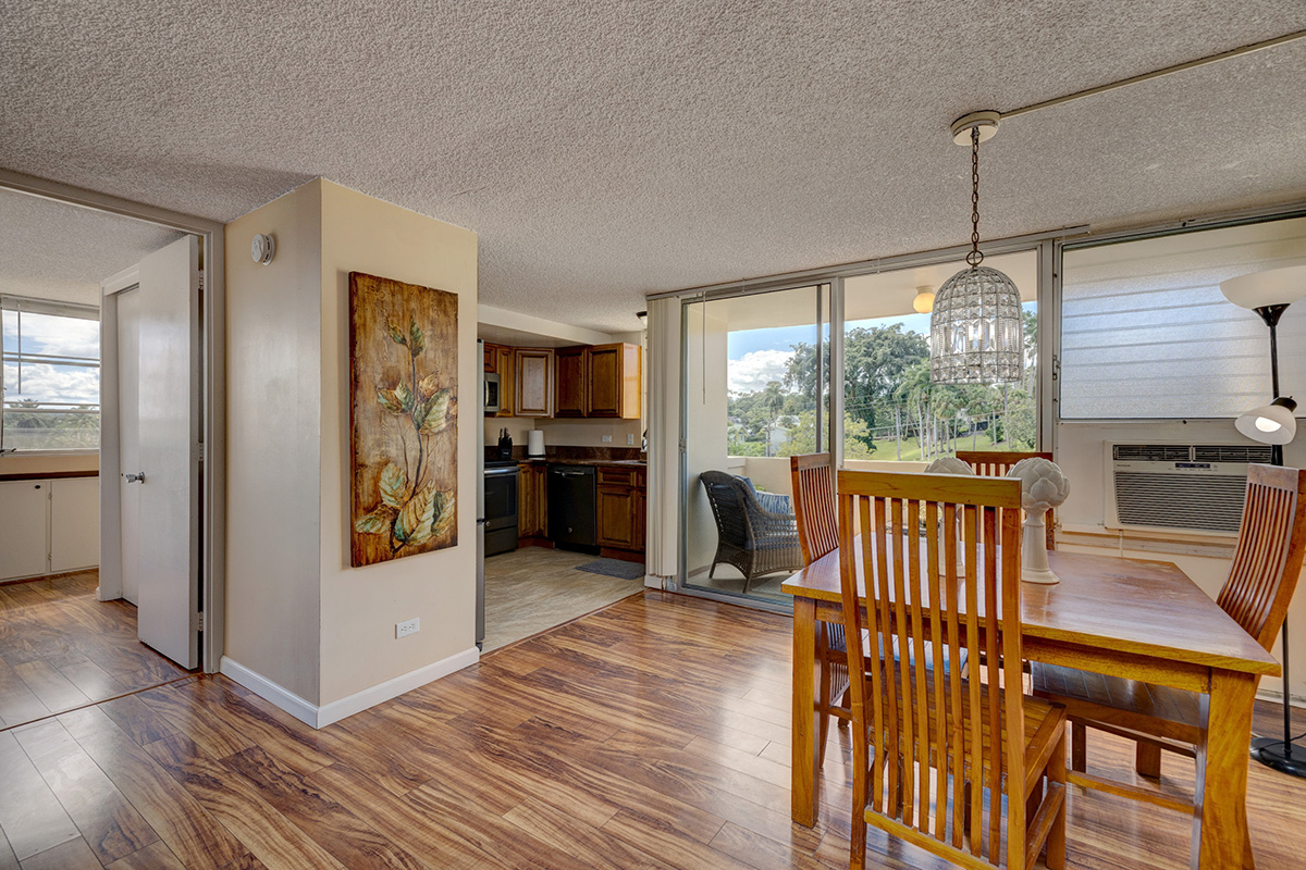 84 Pukihae Street, Unit 406 Hilo, HI 96720 - Photo 5 of 26 a open kitchen with stainless steel appliances granite countertop a refrigerator a stove top oven and a dining table with wooden floor