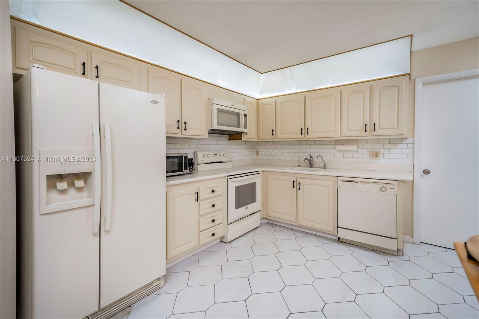 8780 Azalea Court, Unit 104 Tamarac, FL 33321 - Photo 6 of 37 a kitchen with white cabinets and white appliances