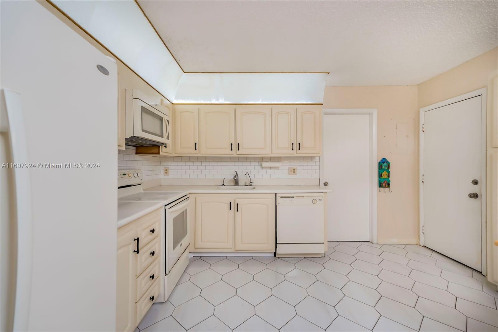 8780 Azalea Court, Unit 104 Tamarac, FL 33321 - Photo 7 of 37 a kitchen with white cabinets and white appliances
