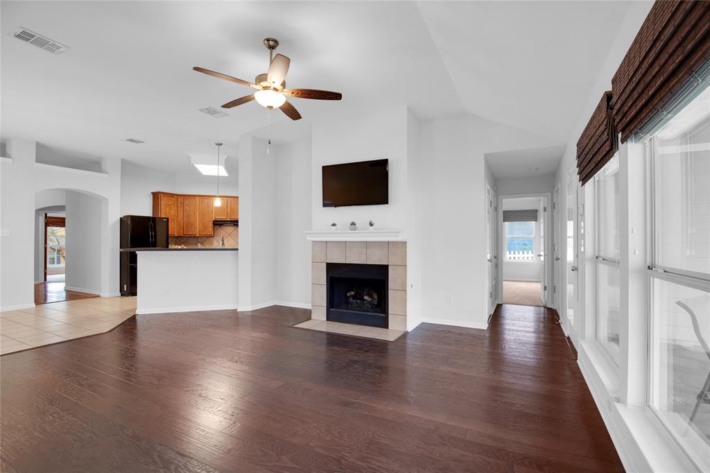 281 Hutton Kyle, TX 78640 - Photo 9 of 37 Rich hardwood floors complement an inviting living area featuring a cozy fireplace and modern kitchen access.