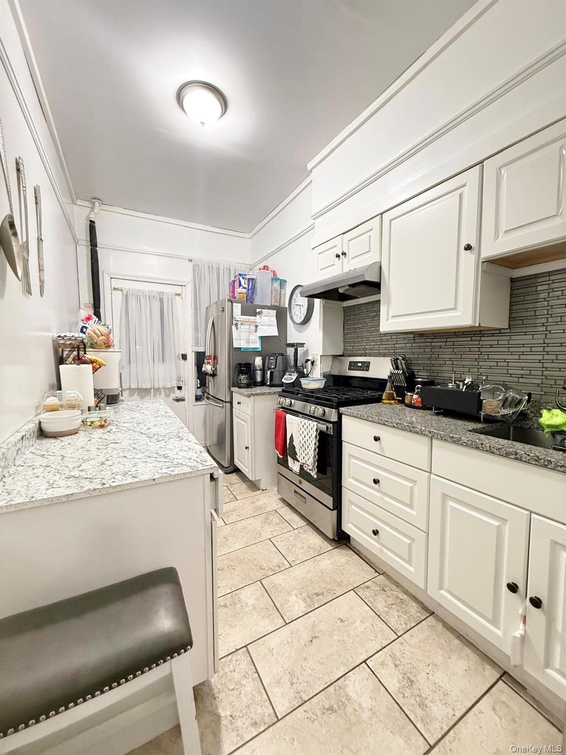 90-13 77th Street Queens, NY 11421 - Photo 8 of 16 a kitchen with granite countertop a stove a sink and a refrigerator