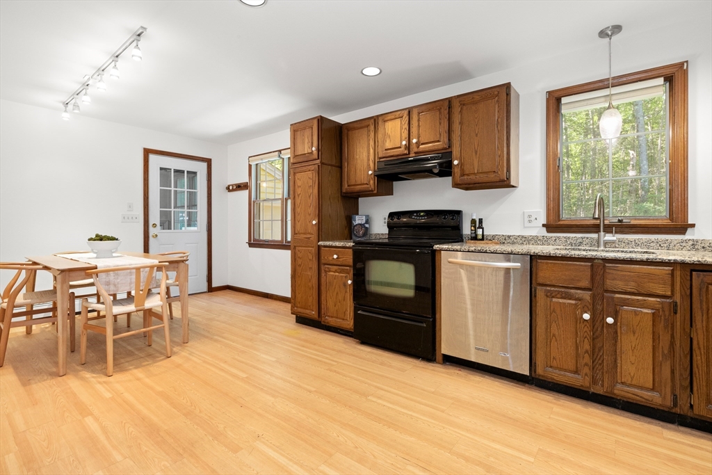 31 Kimball Road Amesbury, MA 01913 - Photo 7 of 40 a kitchen with stainless steel appliances granite countertop wooden cabinets a stove a sink a dining table and chairs
