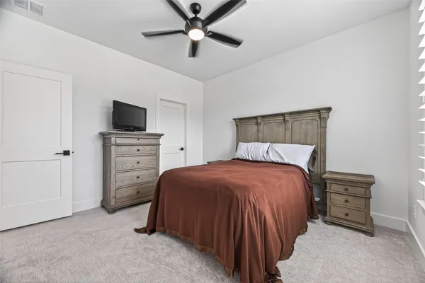 a bedroom with a bed and a flat tv screen on dresser