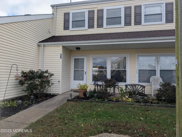 a view of a house with potted plants and a bench