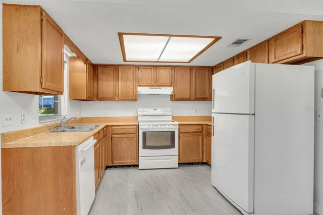 a kitchen with stainless steel appliances granite countertop a refrigerator a sink dishwasher a microwave oven with cabinets and wooden floor