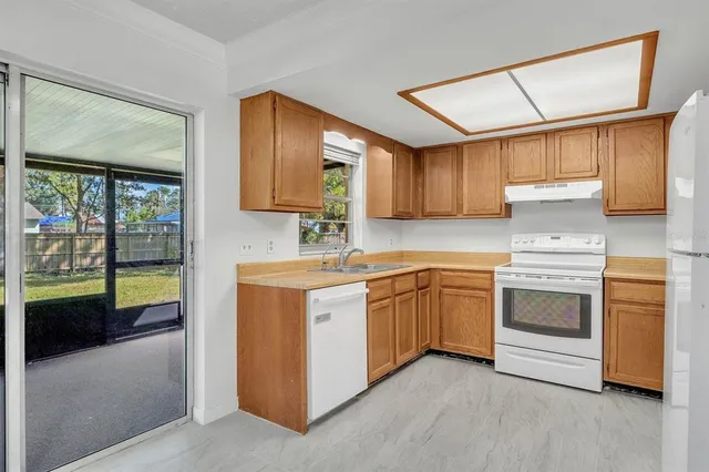 a kitchen with stainless steel appliances granite countertop a stove a sink and a refrigerator with wooden cabinets