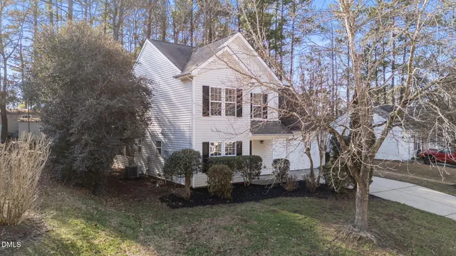 a view of a white house next to a yard with plants and trees