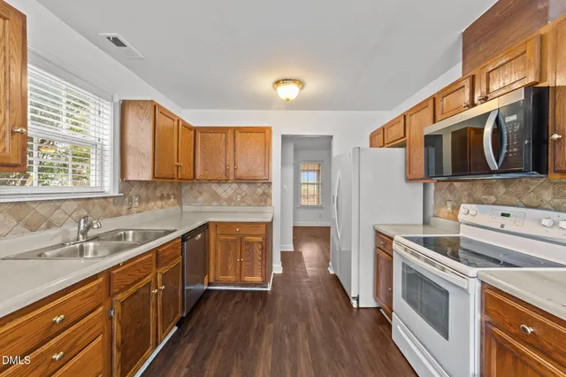 a kitchen with stainless steel appliances a stove a sink cabinets and a wooden floor