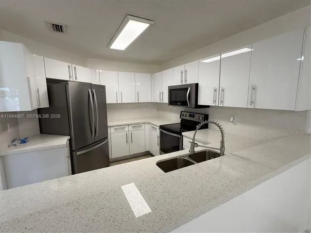 a kitchen with stainless steel appliances granite countertop a refrigerator and a sink