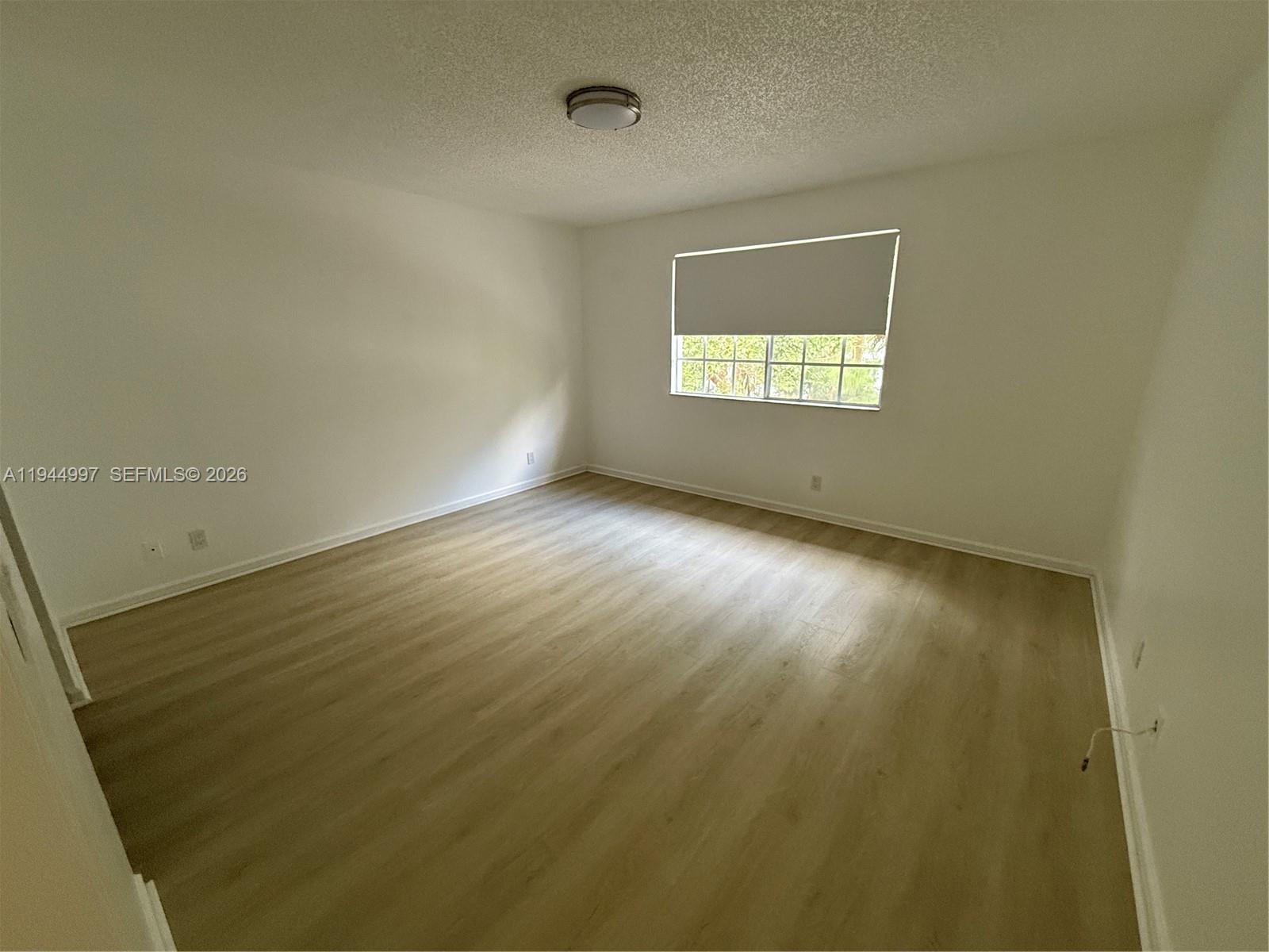 973 Imperial Lake Road, Unit 973 West Palm Beach, FL 33413 - Photo 11 of 28 an empty room with wooden floor and windows