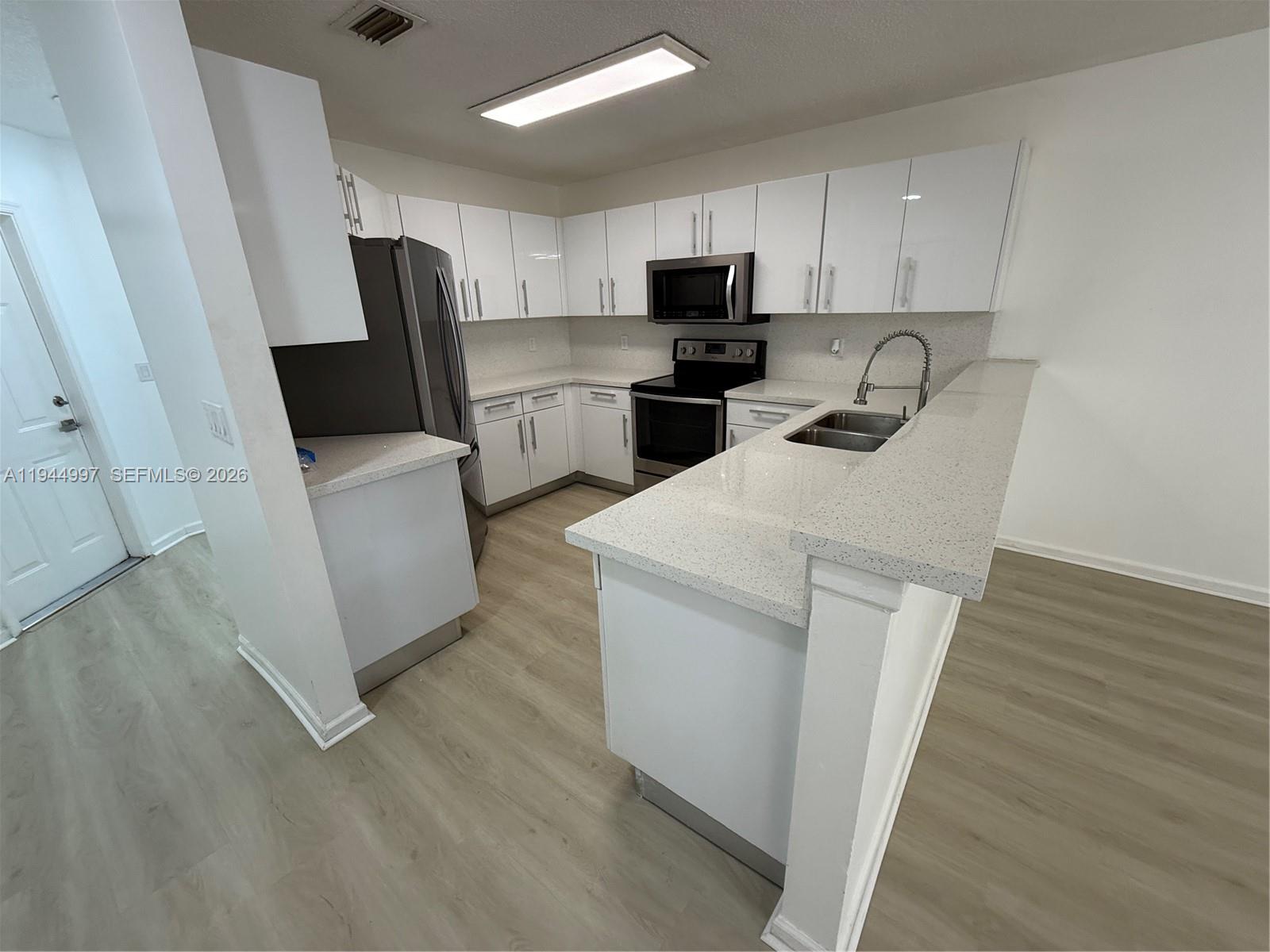 973 Imperial Lake Road, Unit 973 West Palm Beach, FL 33413 - Photo 20 of 28 a kitchen with a sink a refrigerator a microwave and cabinets