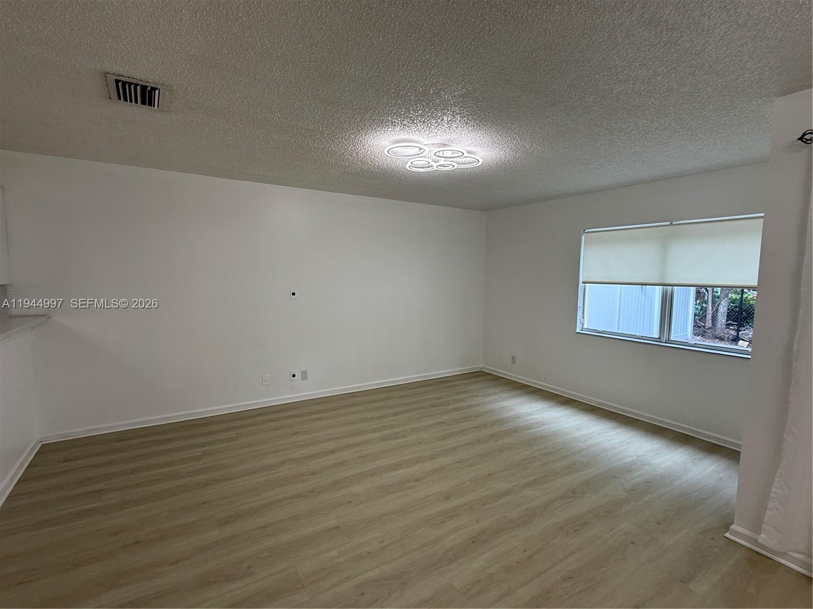 973 Imperial Lake Road, Unit 973 West Palm Beach, FL 33413 - Photo 25 of 28 a view of an empty room with wooden floor and a window