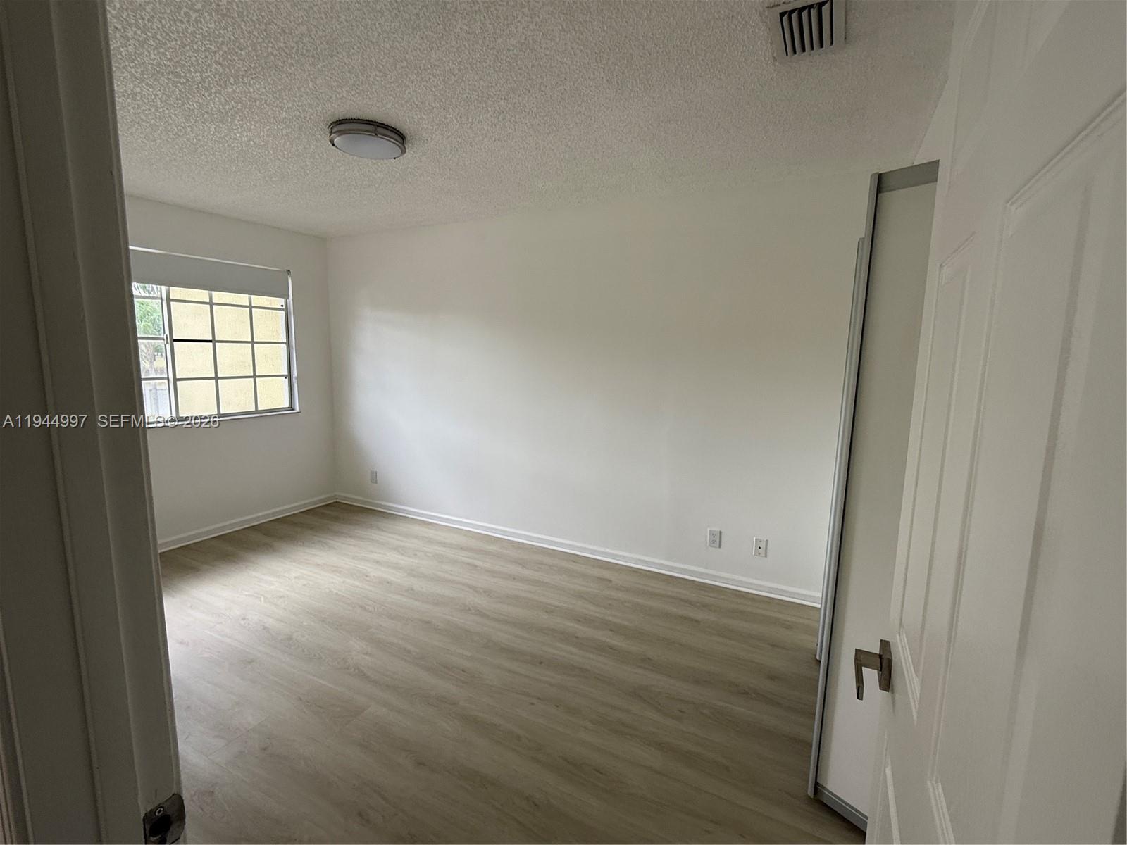 973 Imperial Lake Road, Unit 973 West Palm Beach, FL 33413 - Photo 10 of 28 an empty room with wooden floor and windows