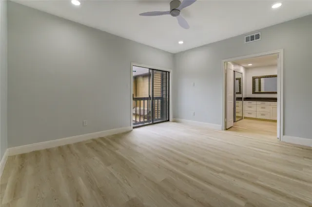 an empty room with wooden floor cabinet and windows
