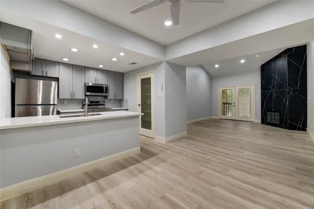 a kitchen with stainless steel appliances granite countertop a sink and a stove top oven with white countertops