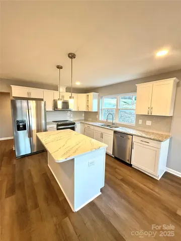a view of a kitchen with kitchen island a large window a sink and a counter top space