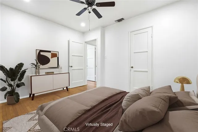 an empty room with wooden floor chandelier fan and windows