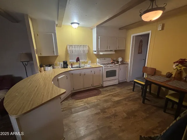 a large kitchen with a table chairs wooden cabinets and wooden floor