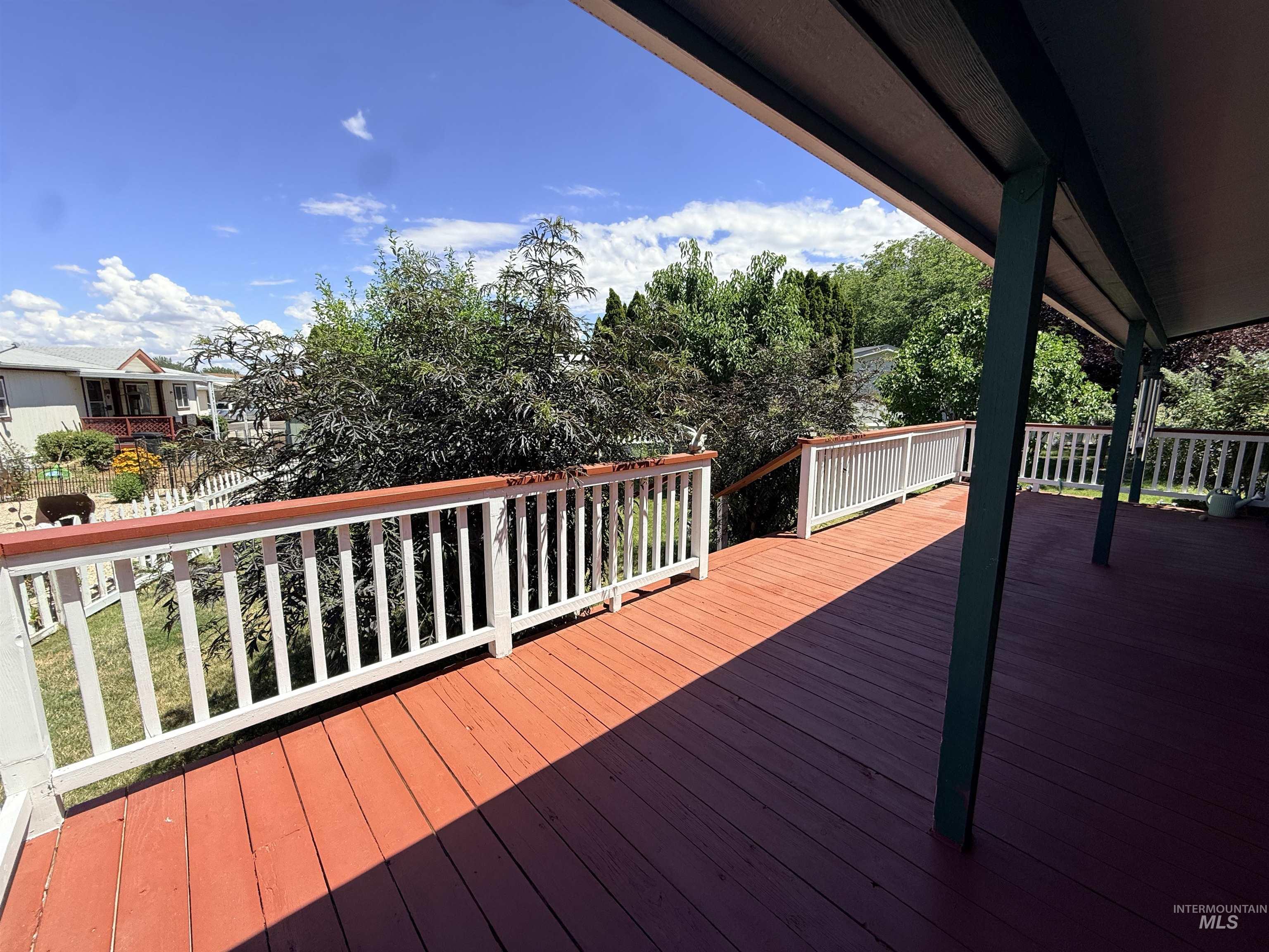 2750 Alden Road, Unit 12 12 Fruitland, ID 83619 - Photo 36 of 38 Expansive outdoor deck with red-stained wood flooring and white railings featuring wood-finish tops