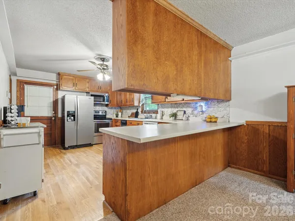 a kitchen with stainless steel appliances granite countertop a sink a stove a refrigerator a washer dryer and white cabinets